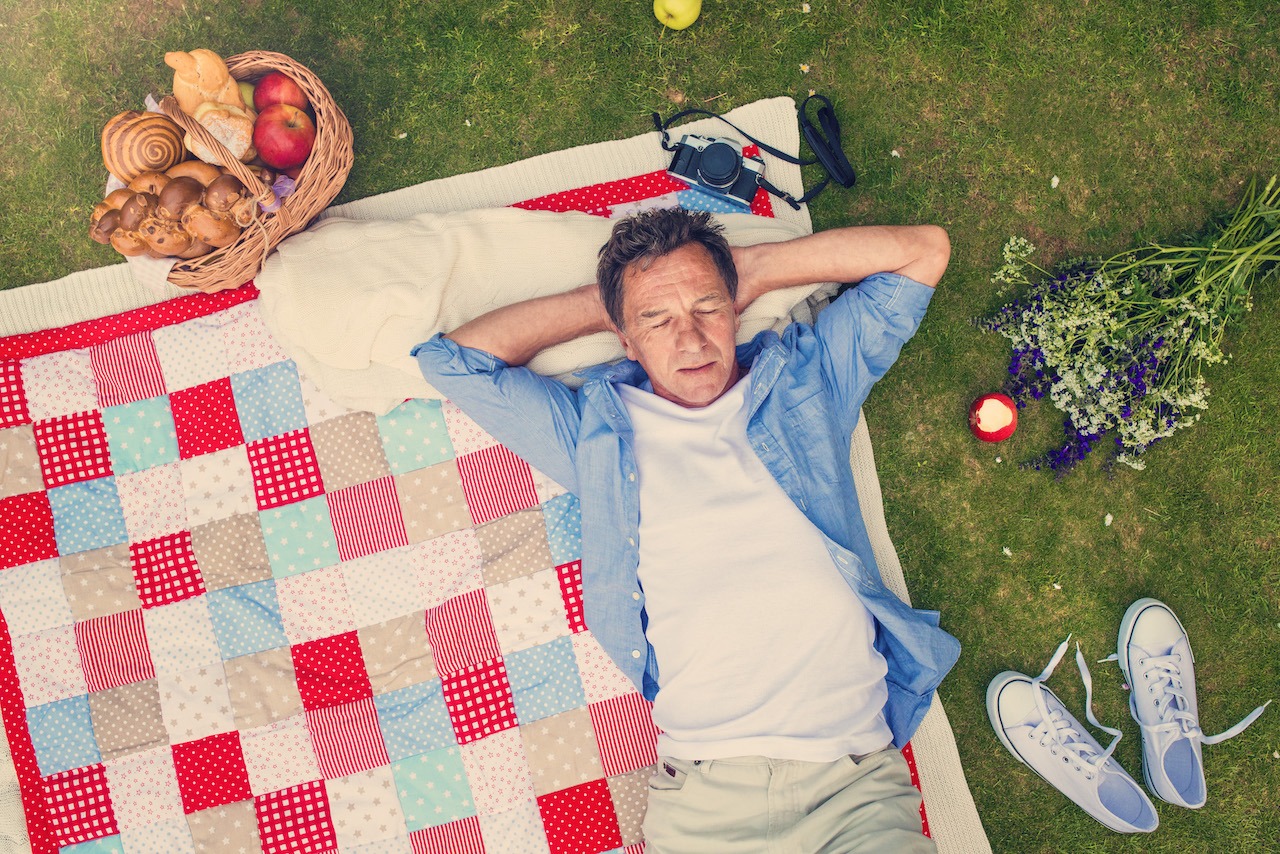 Senior man having a picnic Senior man having a picnic lying on a colorful blanket